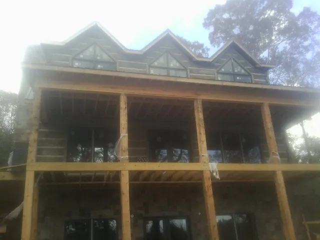 Dormers and porch framing on a large log home under construction — Roof Coating work by our crew in Collegeville