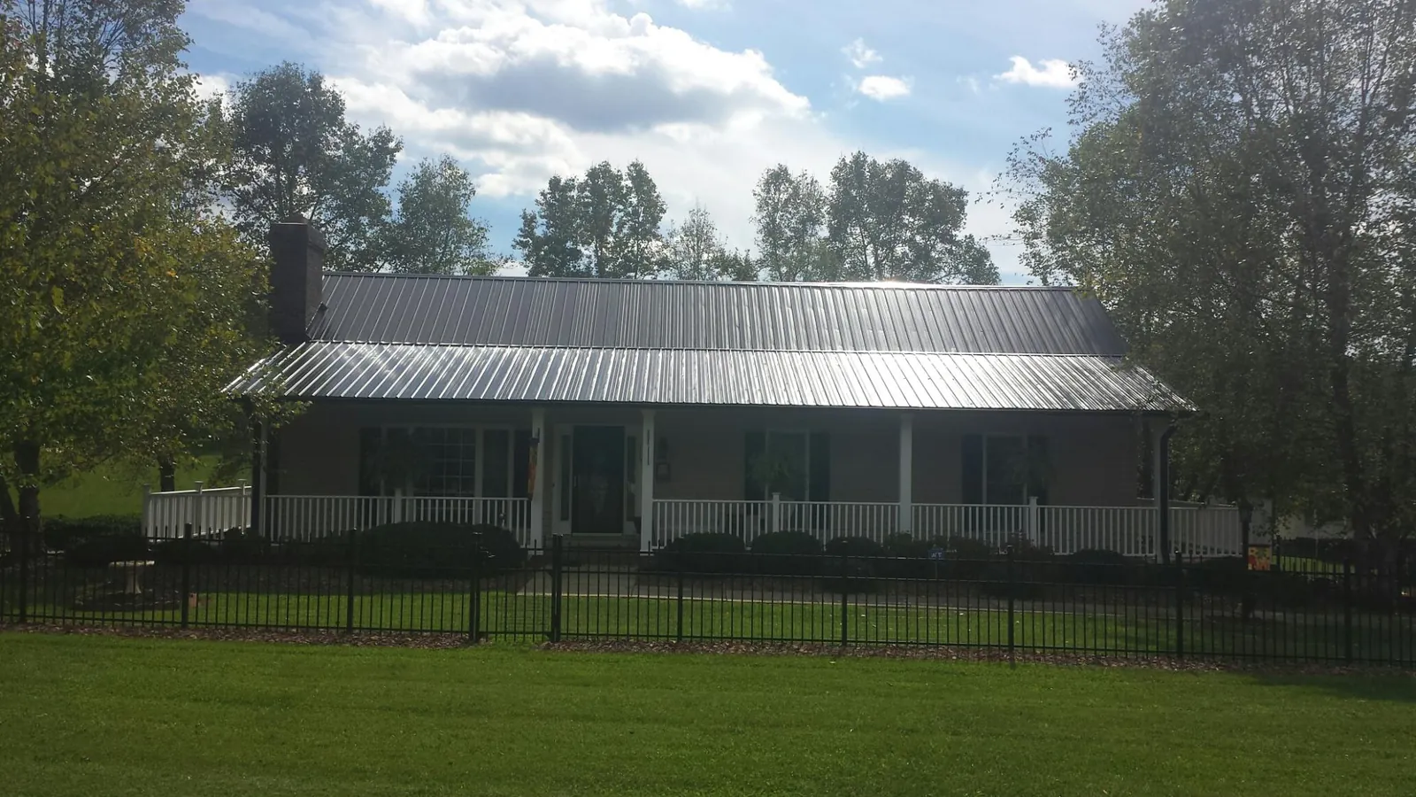 Gray metal roof on a brick ranch with a full width front porch — Gutter Guard Installation work by our crew in Collegeville